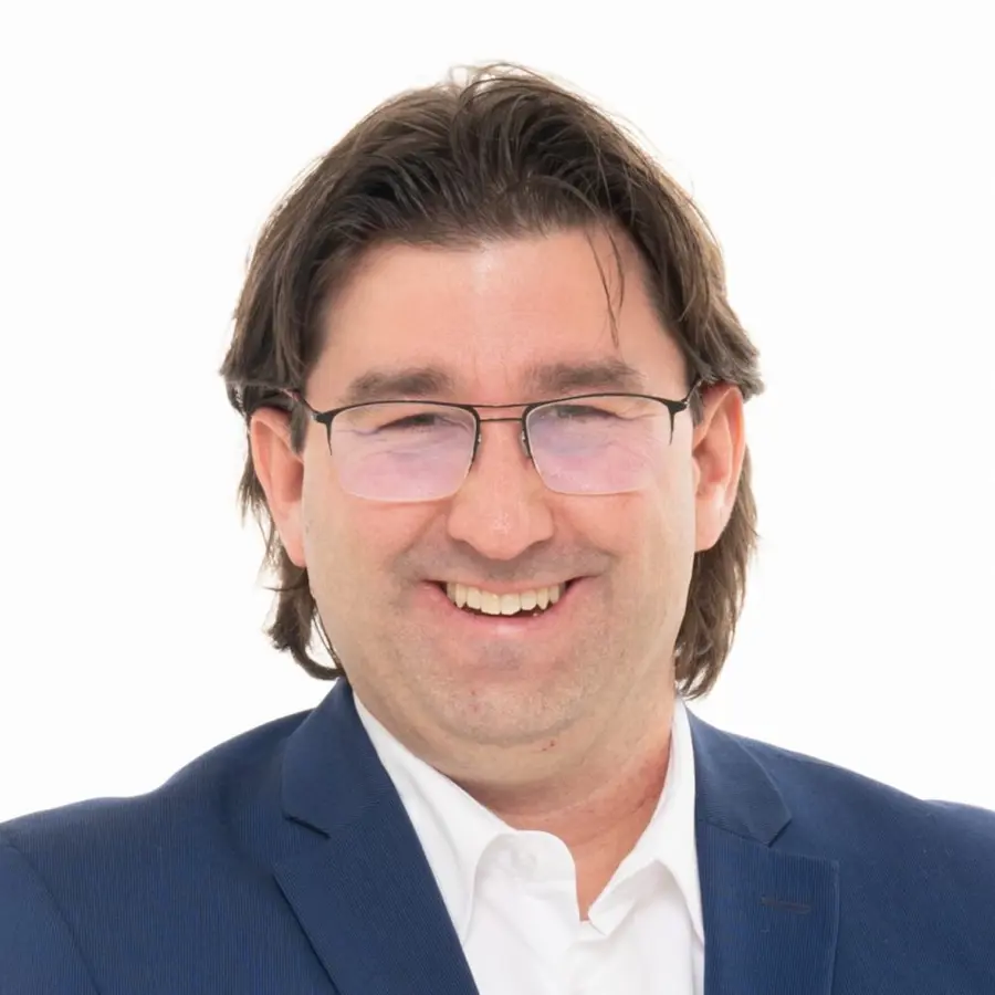 Een profiel foto van John-Paul Straver in een blauw pak met wit overhemd.